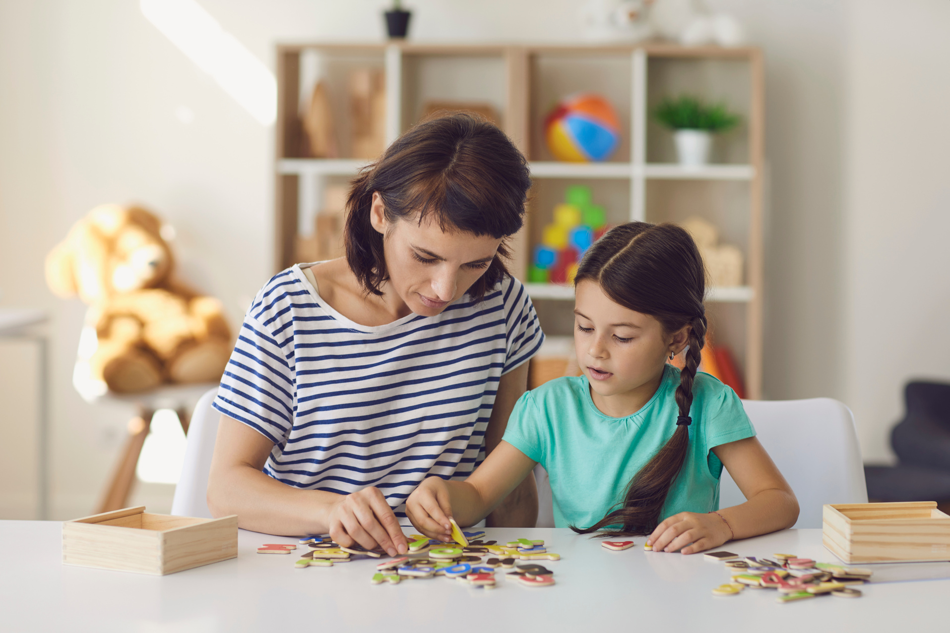 Mother and Daughter Playing Educational Game Arranging Letters into Words in Nursery Room at Home