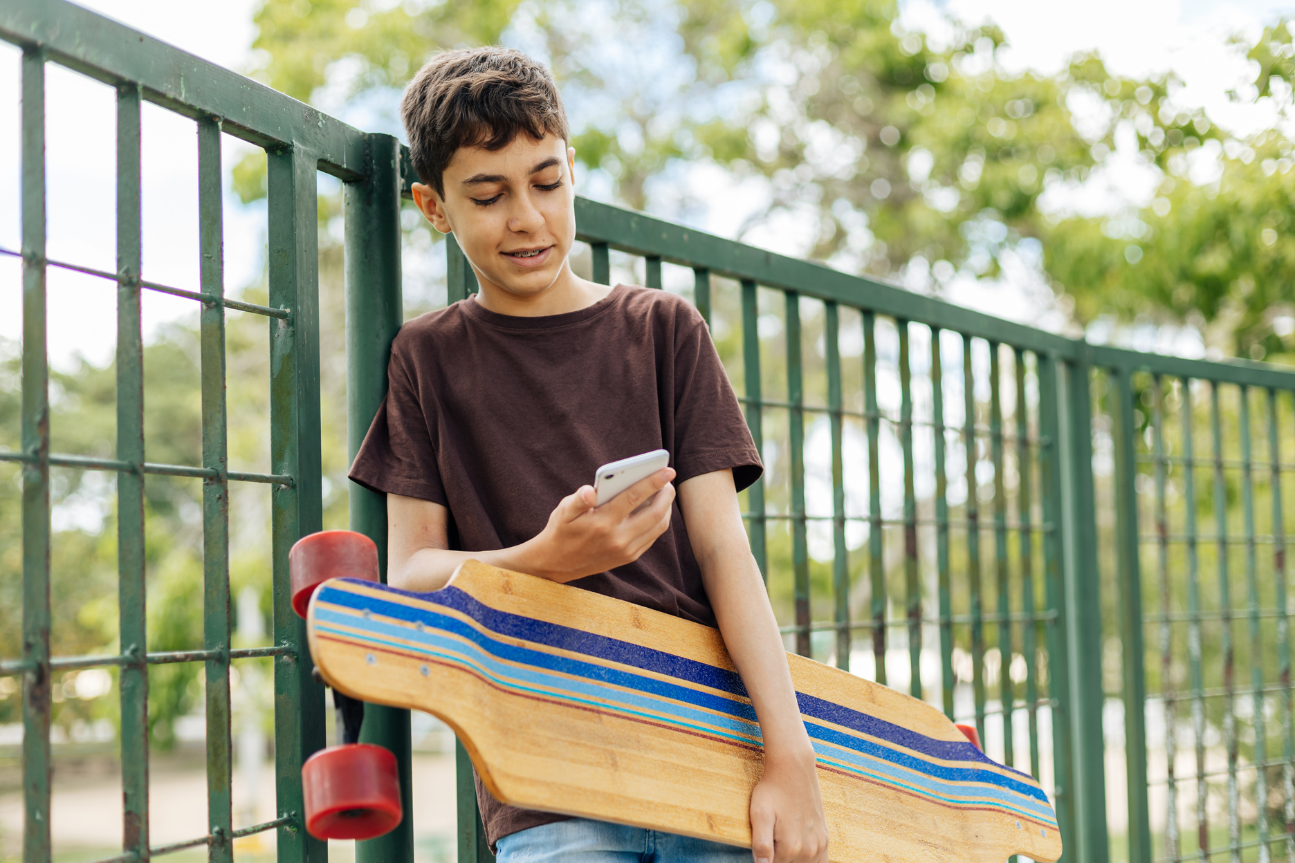 13 years old boy using smartphone outdoors.